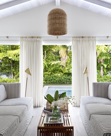 ce bungalow de plage de palmiers conçu par lindsey lane présente des accents côtiers, comme une suspension en rotin et des tables d'appoint, pour un look chaleureux et épuré