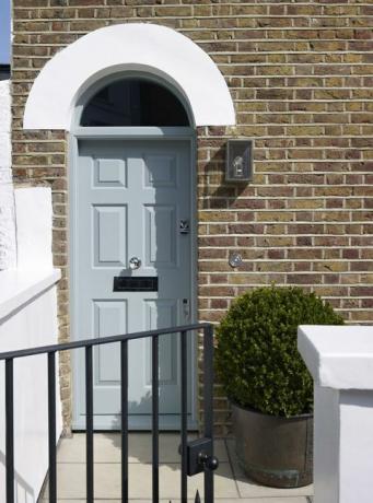 Porte d'entrée bleu pâle dans la maison en brique