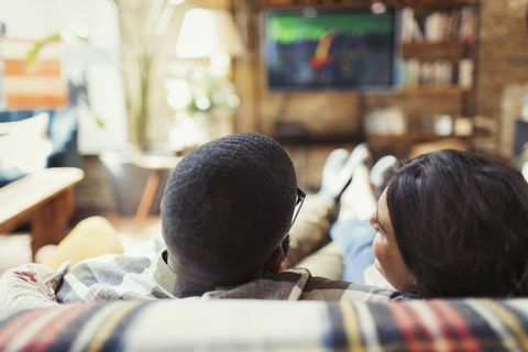 Jeune couple se détendre, regarder la télévision sur le canapé du salon