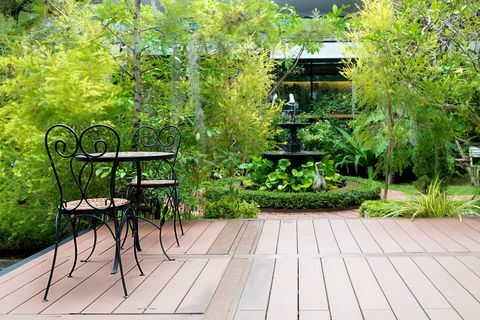 Chaise noire dans le patio en bois au jardin vert avec fontaine dans la maison. Jardin extérieur.