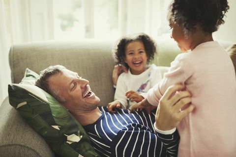 Père et filles chatouillant et riant sur le canapé