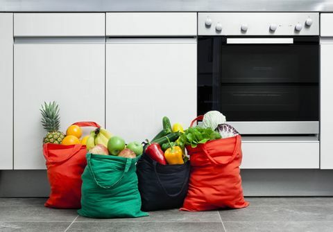 Sacs à provisions réutilisables remplis de fruits et légumes dans une cuisine.