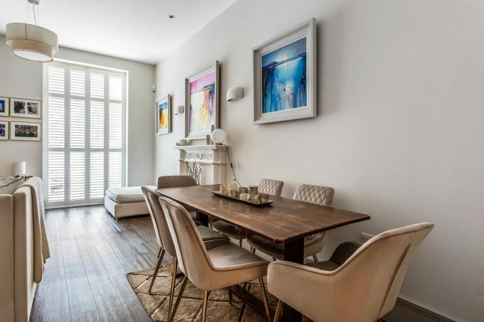 une salle à manger neutre avec cheminée, table en bois et chaises en tissu