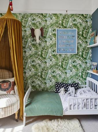 chambre d'enfant avec papier peint imprimé palmiers tropicaux et baldaquin jaune