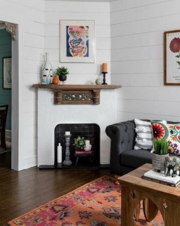 salon, parquet, tapis, table basse en bois, cheminée en carrelage métro blanc et noir, canapé gris foncé avec coussins colorés