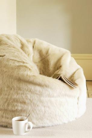 Pouf en fourrure avec livre et tasse à café