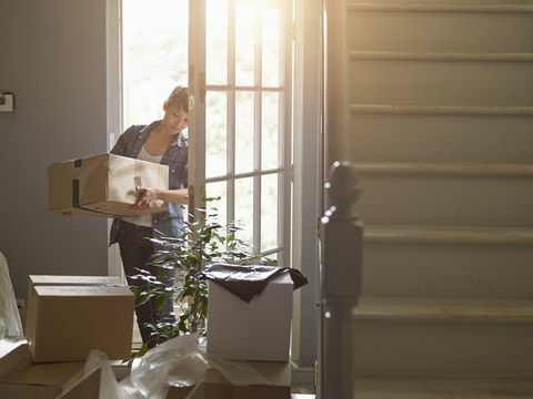 et femme portant une boîte d'emballage dans sa nouvelle maison