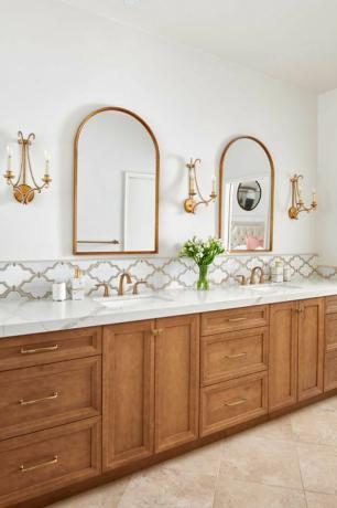 salle de bain blanche, appliques dorées, miroirs dorés, armoires en bois, comptoirs en marbre