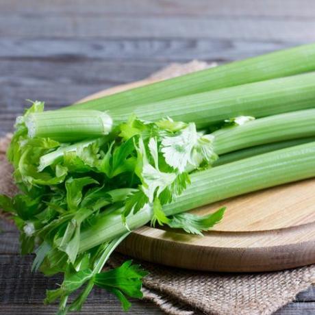 Tiges de céleri vert frais sur une planche à découper en bois