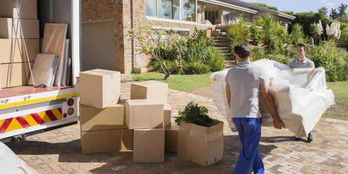 déménageurs transportant un canapé d'un fourgon de déménagement à une maison