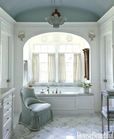 Le plafond en tonneau brillant dans la salle de bain principale est peint dans le puits de lumière de Farrow & Ball. P. E. Luminaires de baignoire Guerin. Chaise DeAngelis en satin Empress par Fret Fabrics.