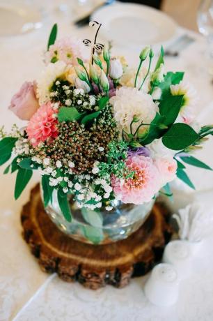 Décoration florale de table de mariage. Vase en verre avec numéro de table pour les invités avec verdure, roses, lisianthus et autres fleurs.