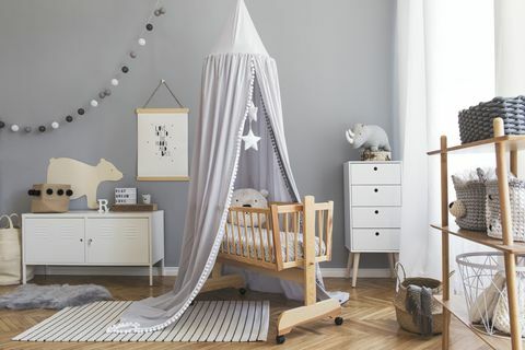 Intérieur de la chambre de bébé nouveau-né scandinave élégant avec maquette, meubles blancs, jouets naturels, baldaquin gris suspendu avec étoiles et ours en peluche. Intérieur minimaliste et confortable de la chambre d'enfant.