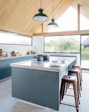 Cuisine bleue avec une barre de petit déjeuner et toit en bois