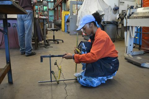 étudiant en sweat orange à genoux tout en travaillant sur l'art