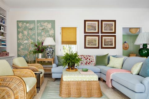 chambre anglaise, canapé-lit bleu, table basse en osier avec coussin de canapé vert et blanc et coussins décoratifs verts et blancs, tapis rose, grande lampe verte