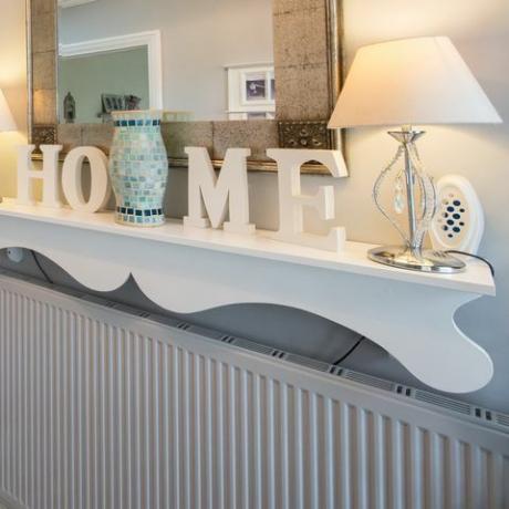 Une vue générale d'un couloir avec carrelage à carreaux noir et blanc, étagère ornée d'escalier en bois nu avec les lettres orthographiant le mot accueil