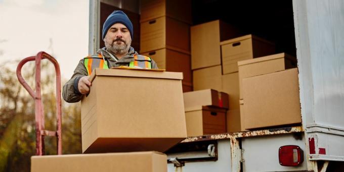 travailleur masculin déchargeant des boîtes en carton d'une camionnette de livraison