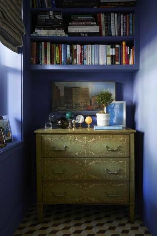 murs peints en bleu, commode verte, boules de marbre, livres décoratifs, plante en pot blanche
