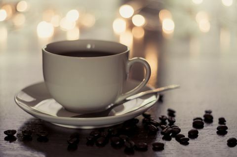 Une tasse et une soucoupe contenant du café étaient assises sur une table parsemée de grains de café.