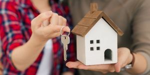 Couple avec clés et modélisation de maison en bois