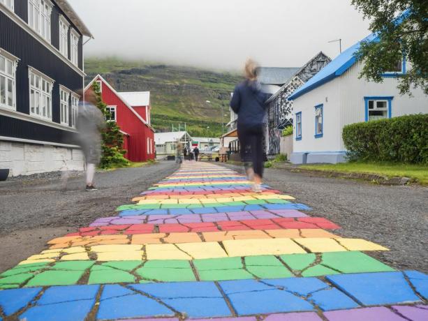 l'islande, seydisfjordur, les gens marchant le long de la route goudronnée de couleur arc-en-ciel au milieu d'une ville isolée