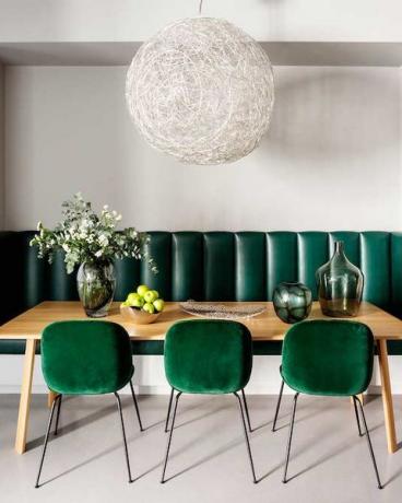 Salle à manger avec des chaises vert émeraude et une lumière de déclaration