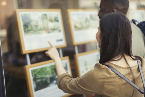 Jeune couple parcourant les annonces immobilières à la devanture