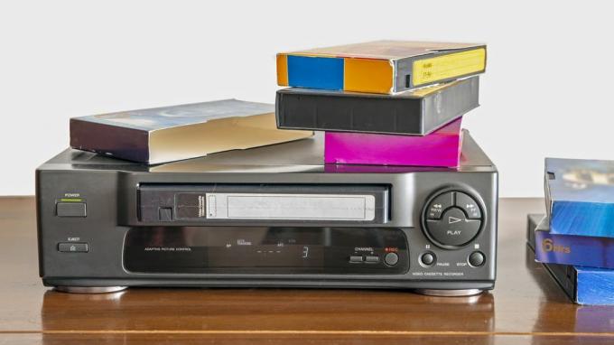 Ancien lecteur de cassettes vidéo avec de vieilles cassettes vidéo sur une armoire en bois